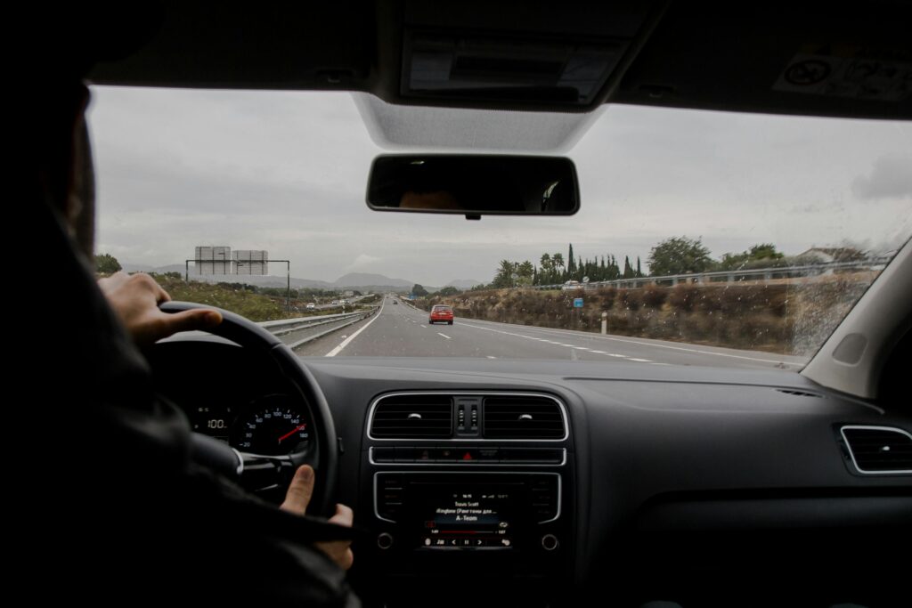 Anonymous man driving fast along asphalt road on modern vehicle in overcast weather