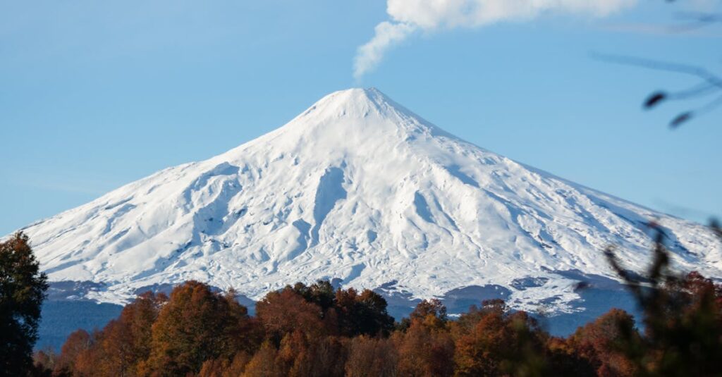 Majestic view of Villarrica Volcano with autumn foliage and lake reflections.