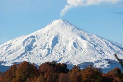 Majestic view of Villarrica Volcano with autumn foliage and lake reflections.